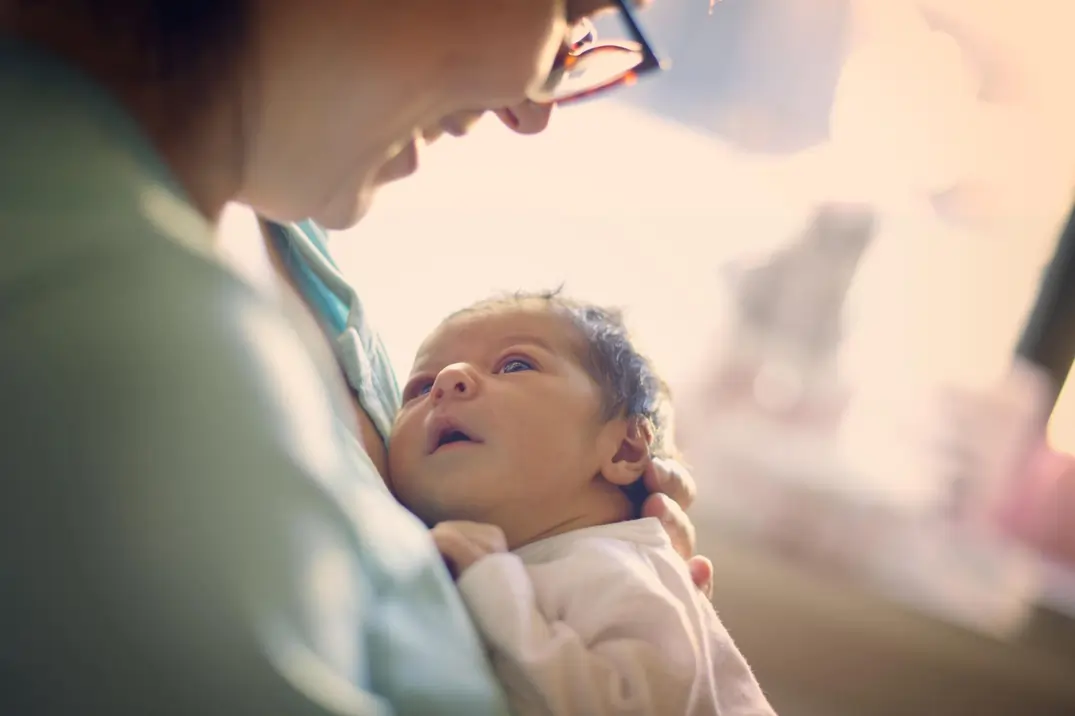 a new born baby looking at her mom and her mom is smiling